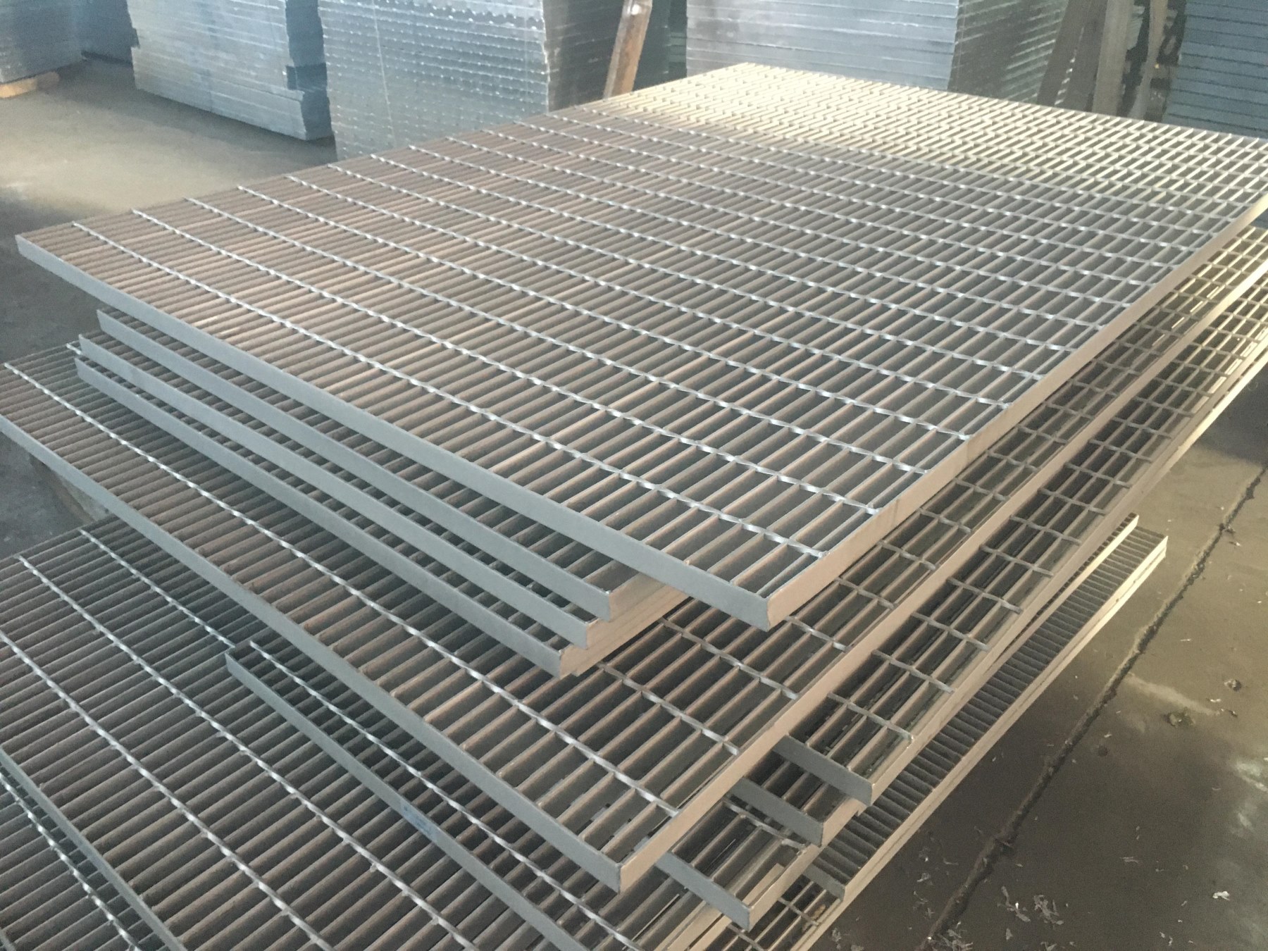 Stacked stainless steel grating panels in workshop