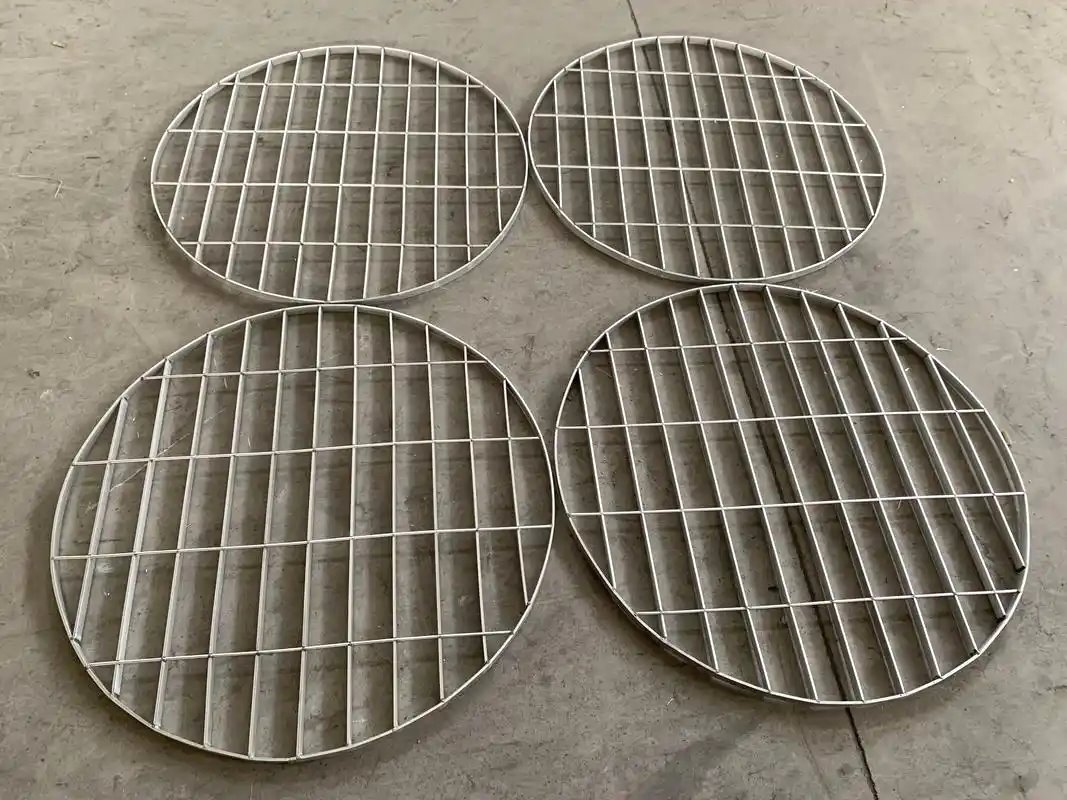 Four circular steel grating panels arranged on a workshop floor.