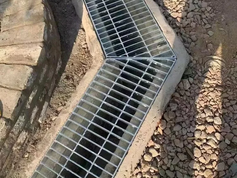 Curved steel grating drain cover in outdoor trench
