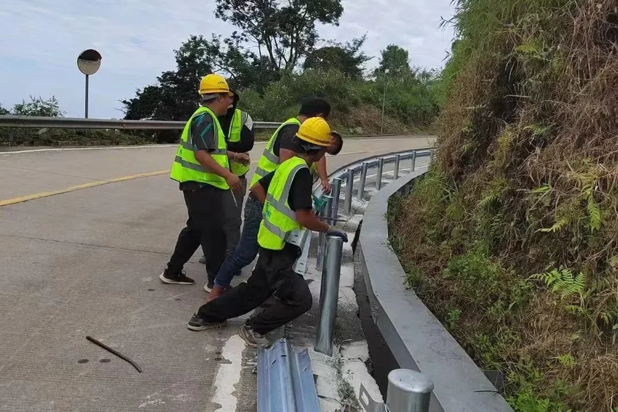 Workers installing highway guardrail beams and posts